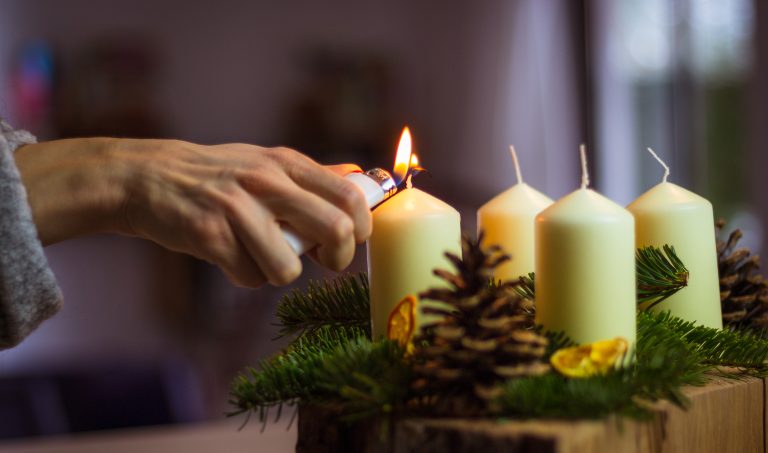 Mano encendiendo la primera vela de Adviento